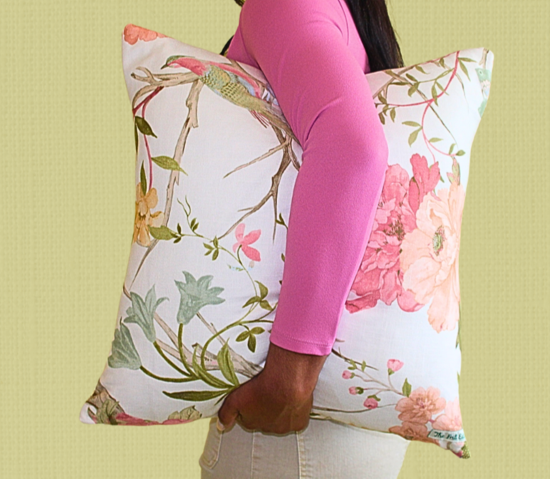 Person holding a floral-patterned pillow against a light green background
